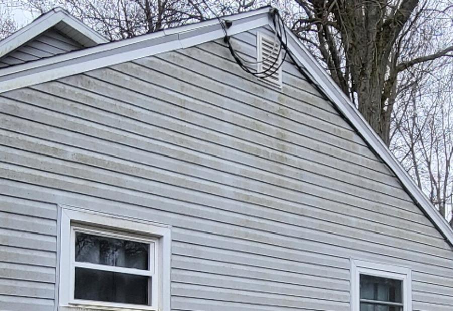 Gable siding with algae streaks washed clean — before